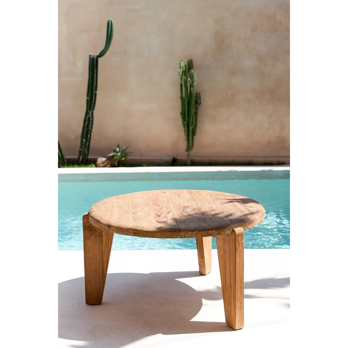 Table en bois près de piscine et cactus.